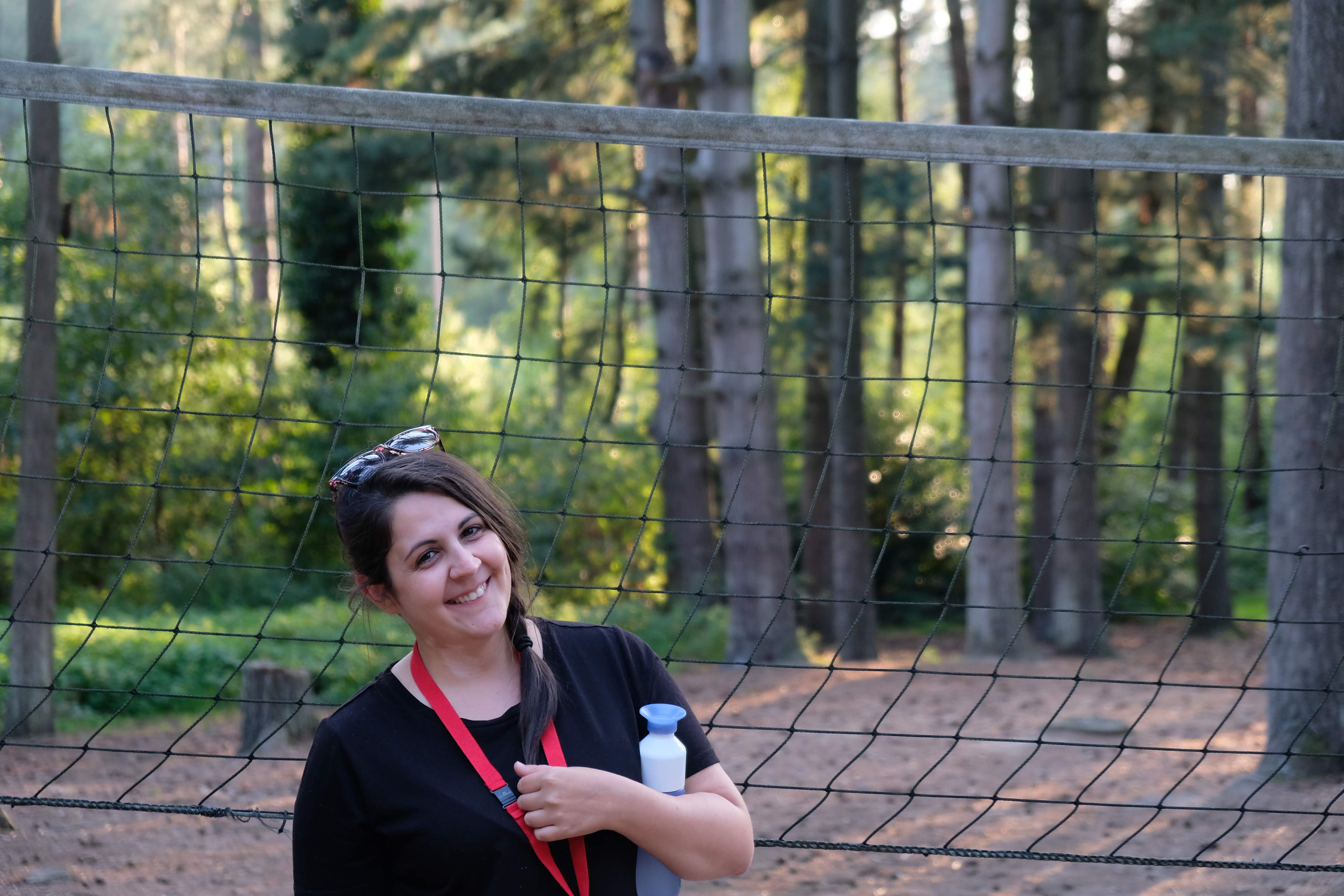 Egy erdei háttér előtt a focikapuban álló mosolygó lány