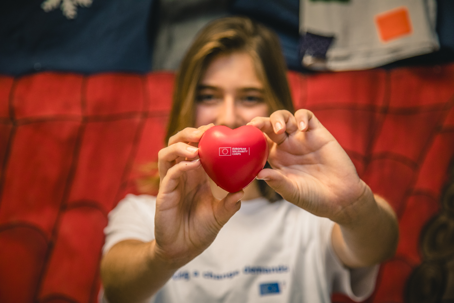 European Solidarity Corps felirat egy piros szívalakú labdán melyet egy fiatal lány tart a kezében 