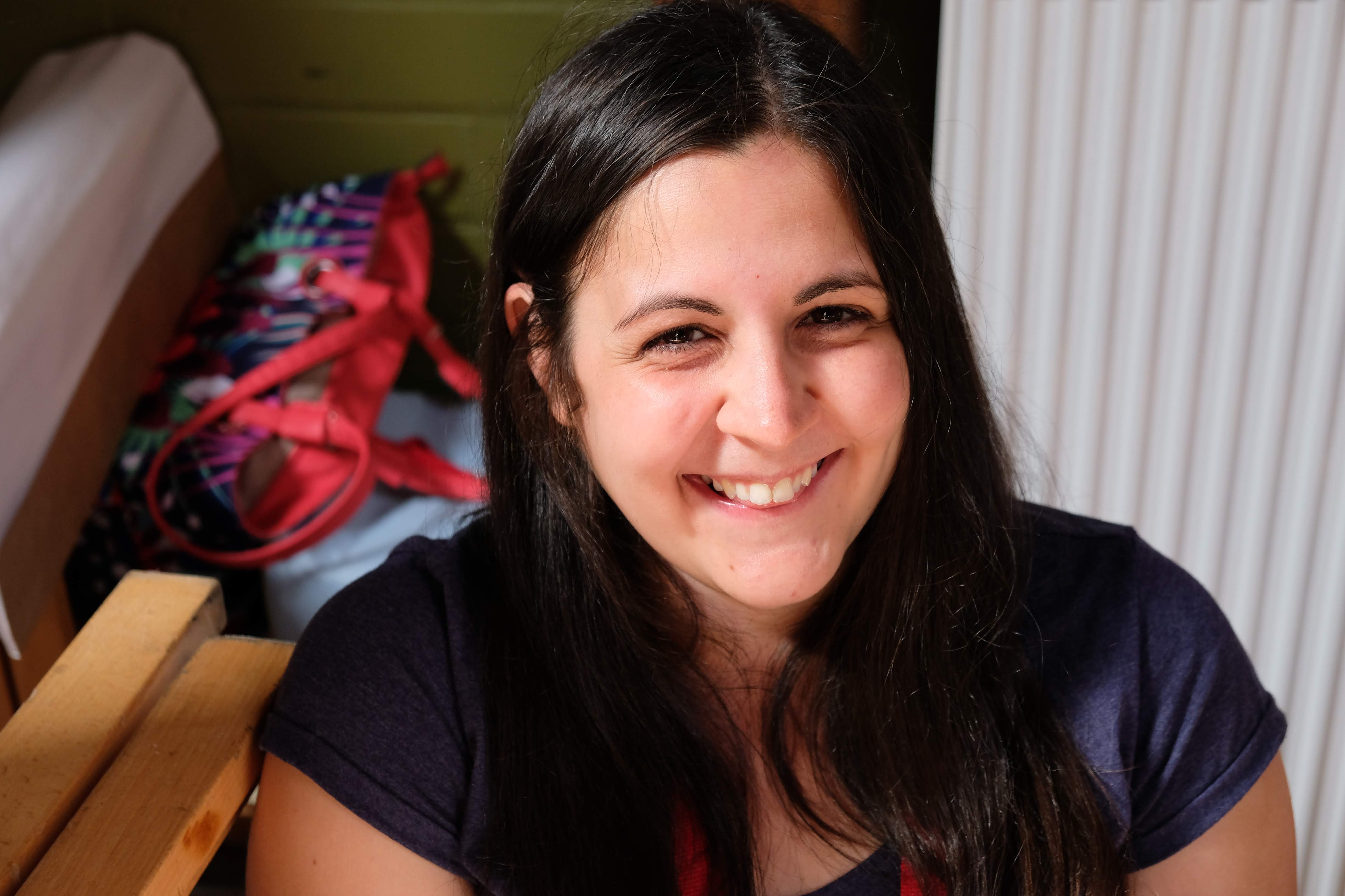 Vinczi Alexandra mosolygó arccal néz a kamerába egy szobában